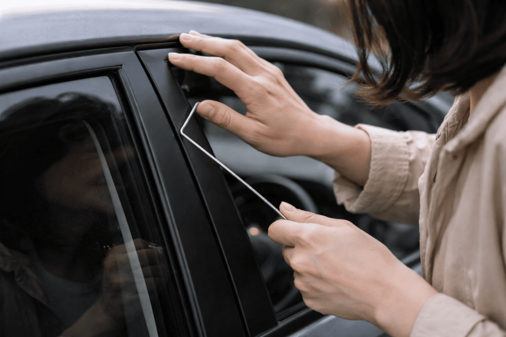 針金を窓の隙間に差し込もうとしている危険な解錠行為のクローズアップ。