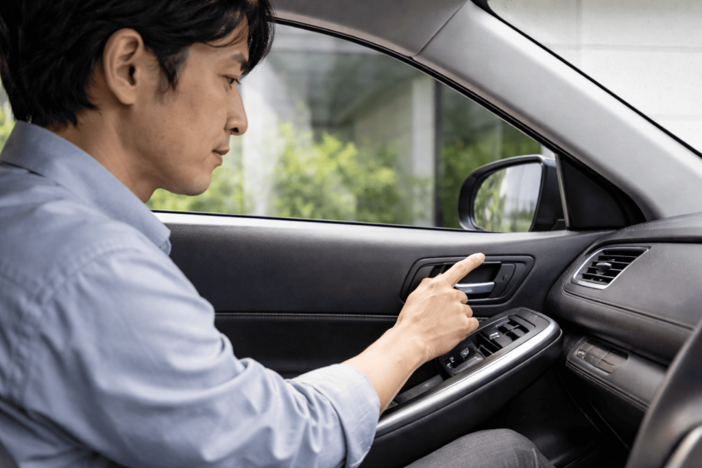 日本人男性が車内でパワーウィンドウスイッチを引き上げ、初期化手順を行っている様子